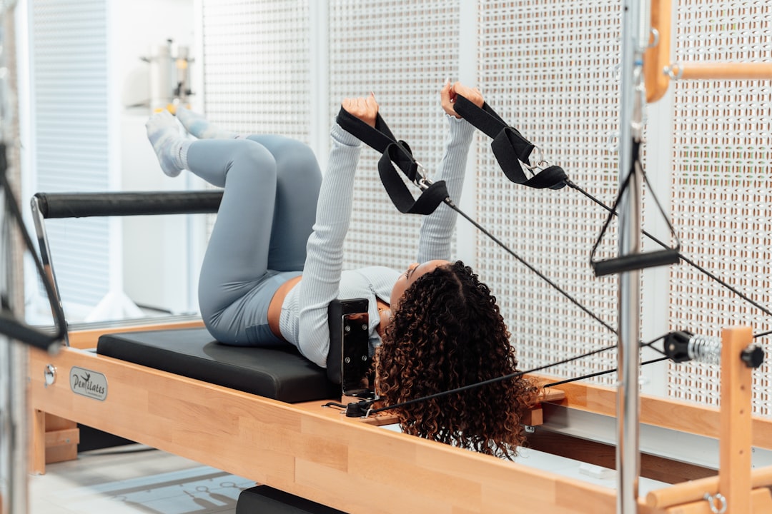 a woman is doing exercises on a rowing machine — Foto: Ahmet Kurt/Unsplash